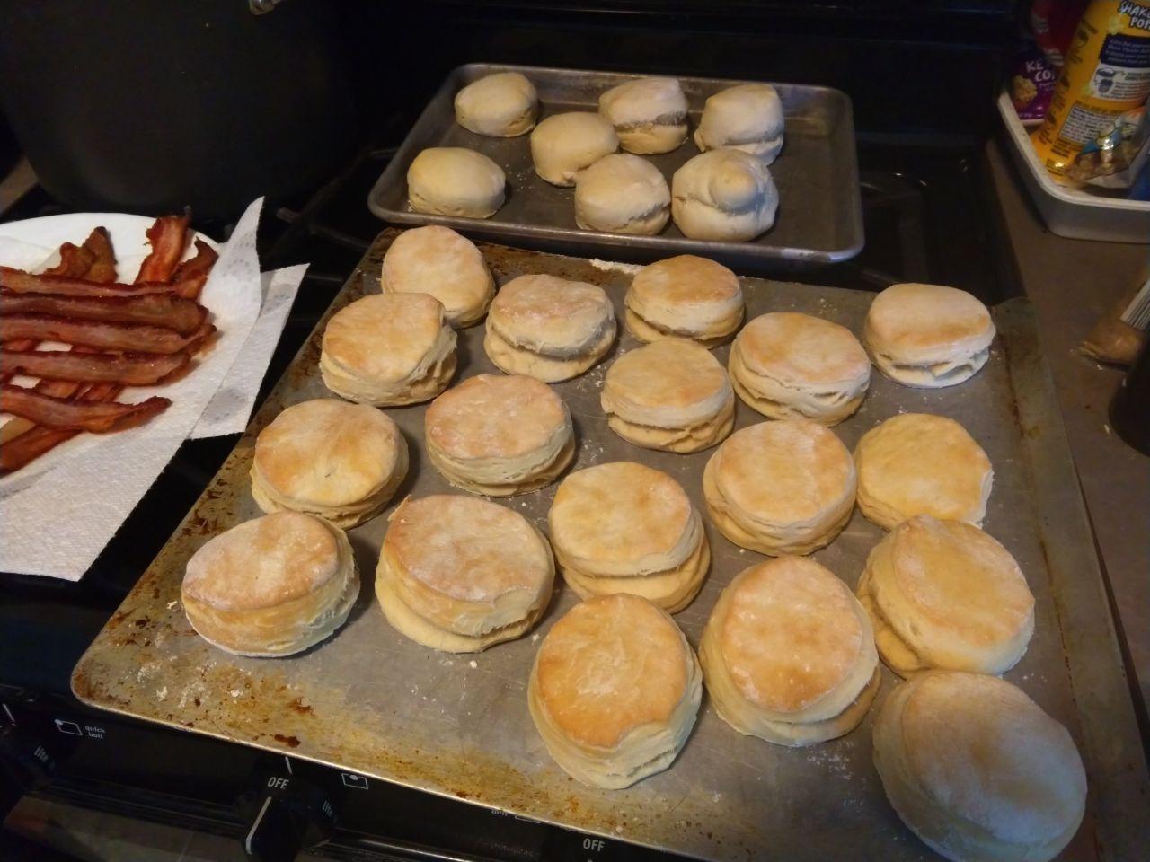 Pan of biscuits out of the oven next to a plate of bacon.