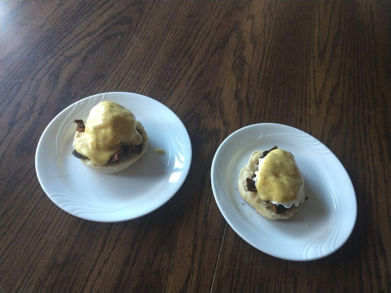 Eggs benedict with a split english muffin, bacon, poached egg, and hollandaise.