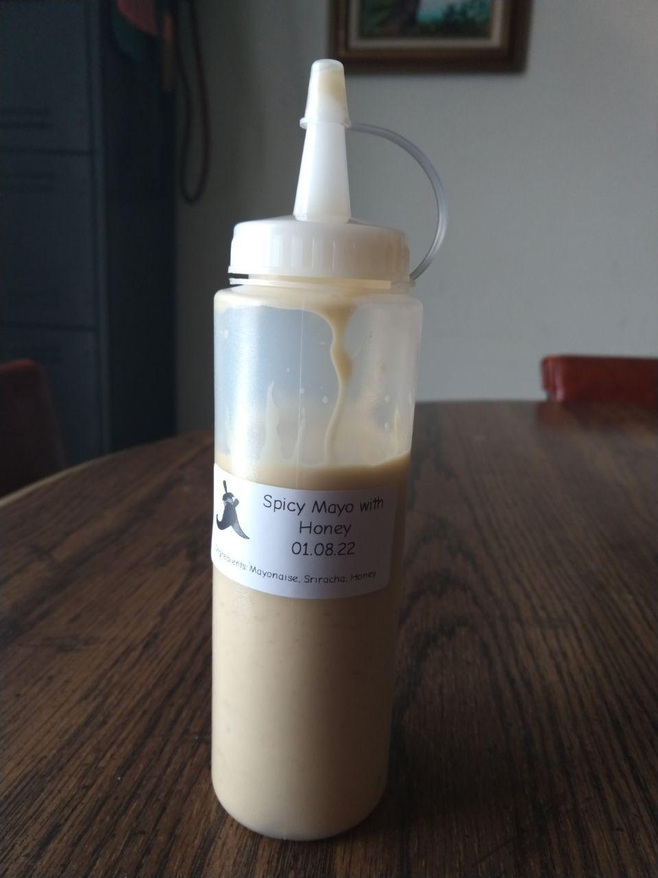 Bottle of spicy mayo made with homemade sriracha, mayonaise, and honey. Bottle of spicy mayo made with homemade sriracha, mayonaise, and honey.