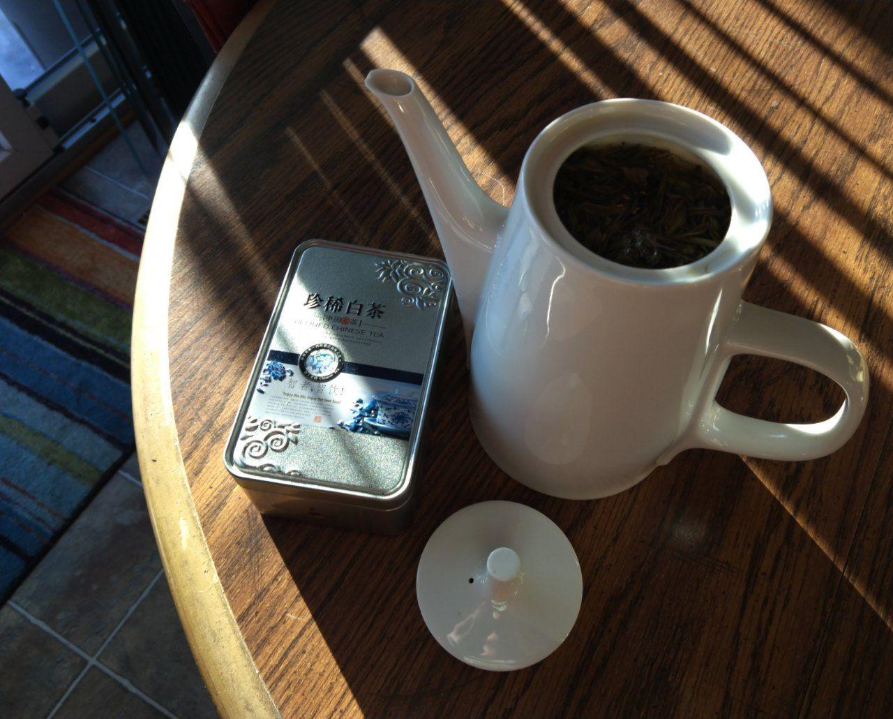 Tea tin next to a teapot with tea brewing in it.